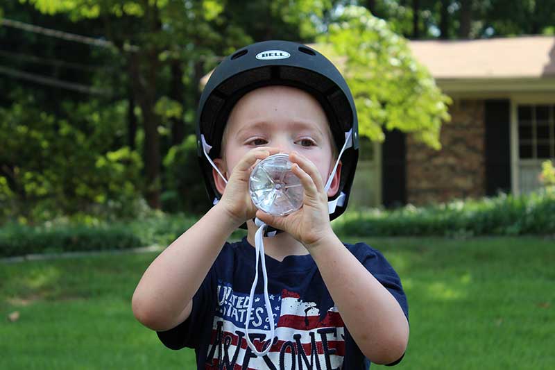 kid wearing bike helmet drinking water