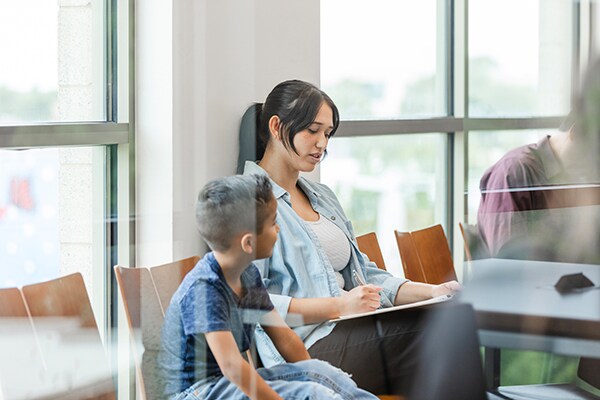 Mom filling out paperwork in waiting room with child sitting next to her
