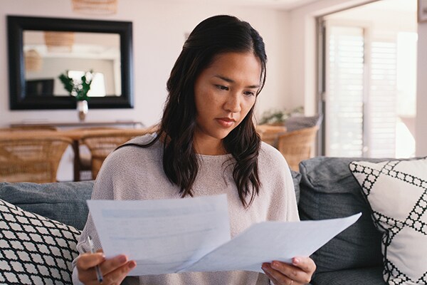 Parent looking over confusing health insurance paperwork in her living room