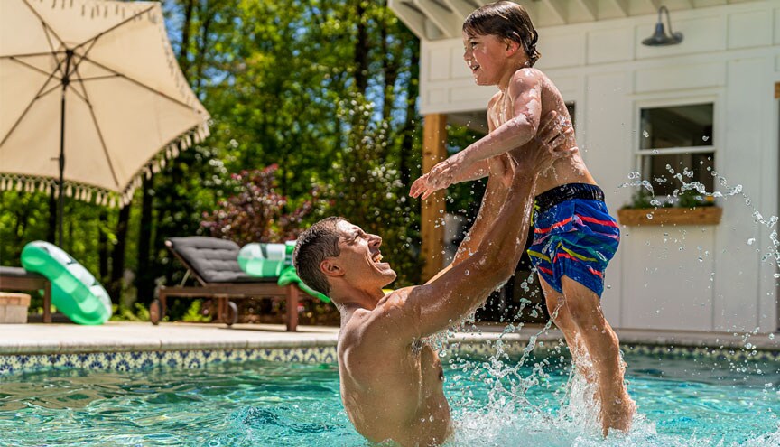 Dad lifting toddler out of pool