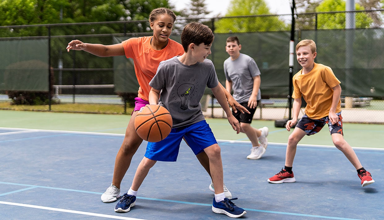 Group of middle school kids playing pick-up basketball, having fun