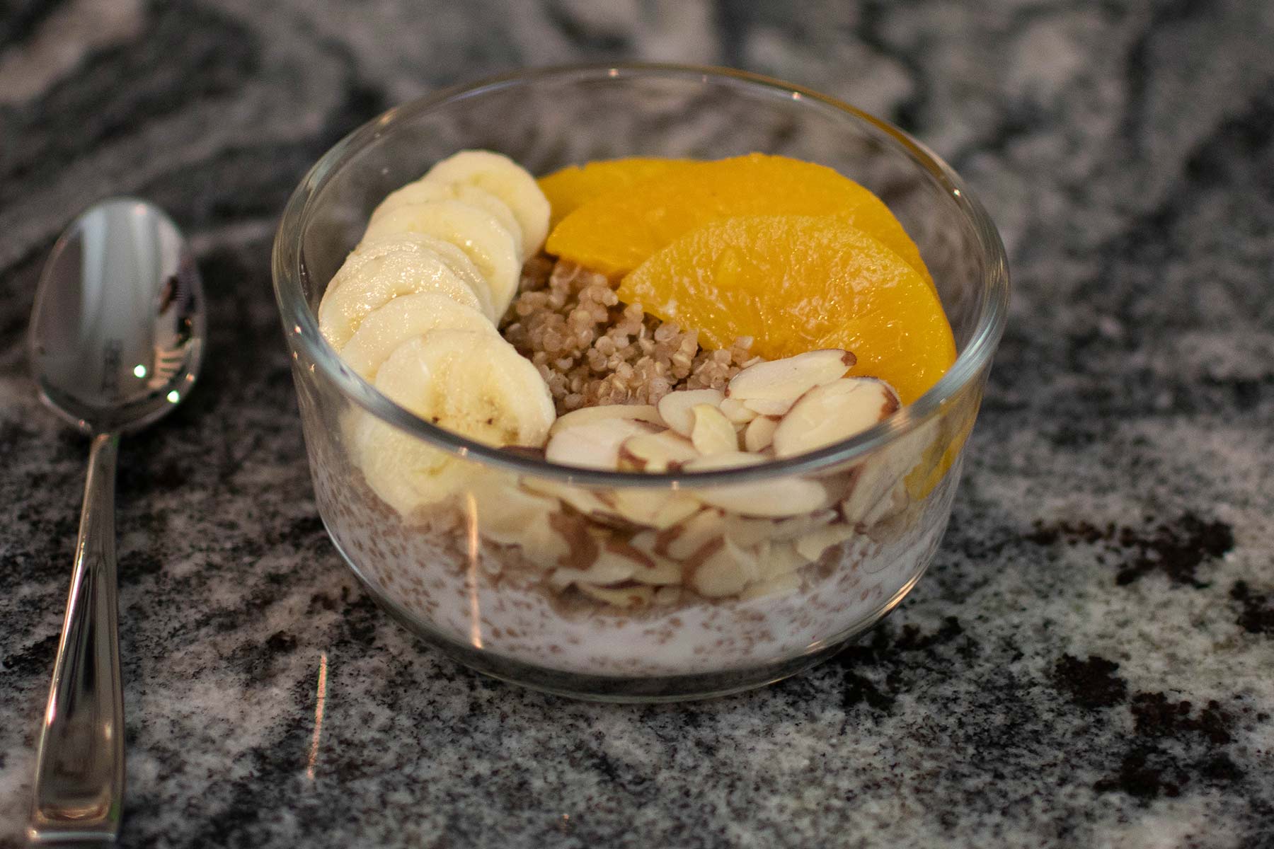 Quinoa breakfast bowl with bananas, almonds, oranges and granola
