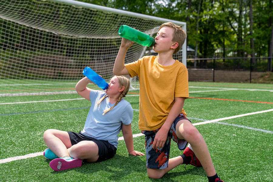 kids drinking water on soccer field