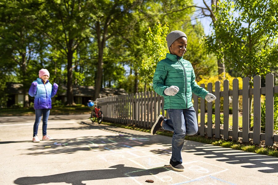 School-aged boy and girl playing hopscotch in driveway