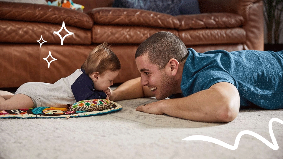 Photo shows dad and baby doing tummy time at 2 months