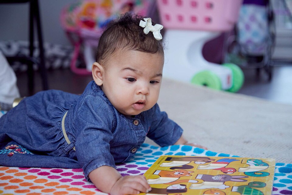 Photo shows baby playing with toy during tummy time at 6 months