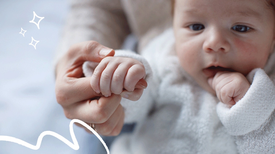 2-month-old baby closes their hand around their parent or caregiver’s finger