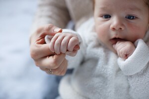 2-month-old baby closes their hand around their parent or caregiver’s finger