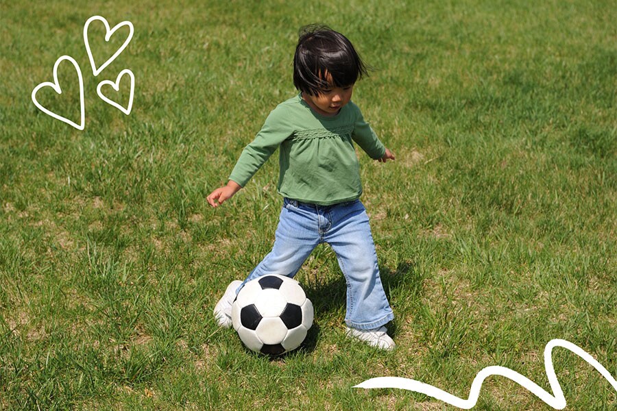 A toddler achieves the movement milestone of kicking a ball.