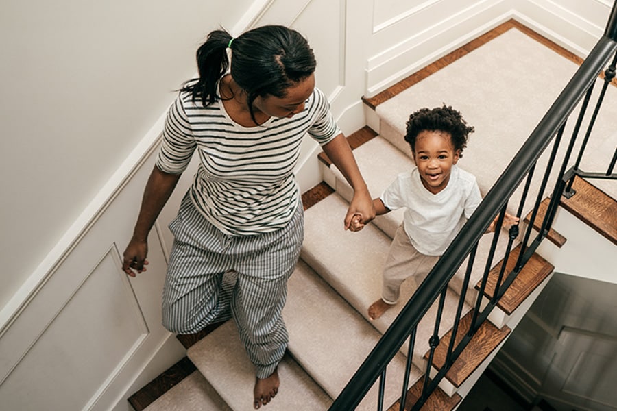 Toddler holding hands with parent as they walk down the stairs together