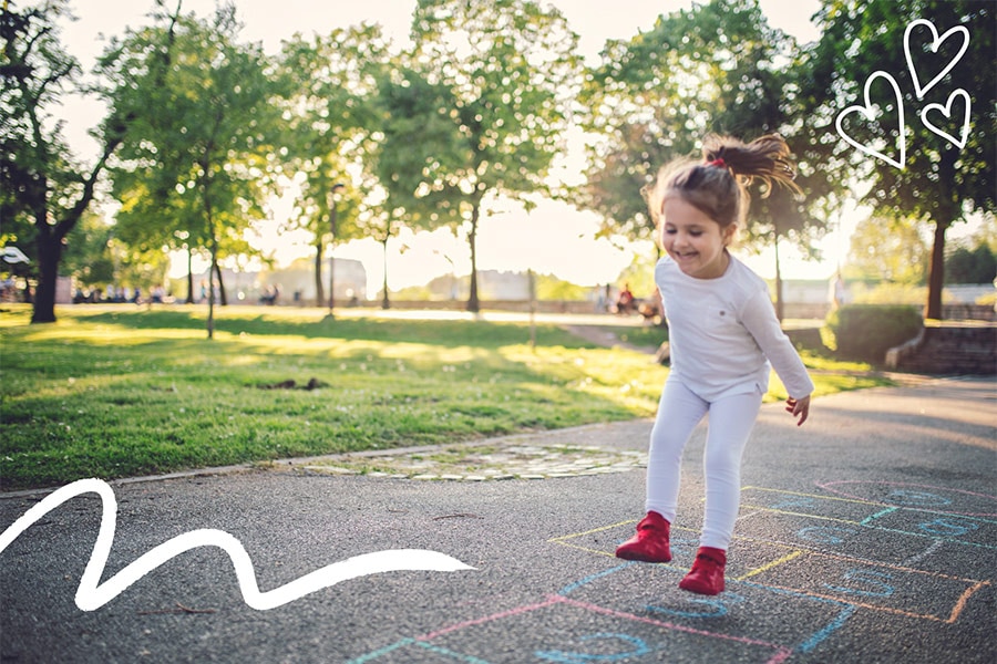 A preschooler plays hopscotch, one of our recommended activities for 3-year-olds.