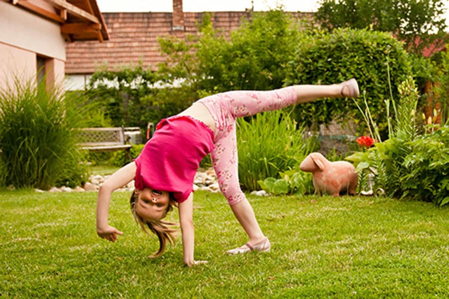 A young child practices milestones for 4- to 5-year-olds by attempting their first cartwheel.
