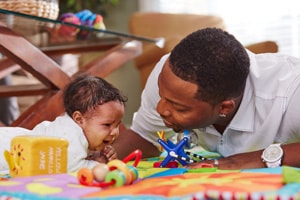 Infant cries during tummy time while dad provides comfort