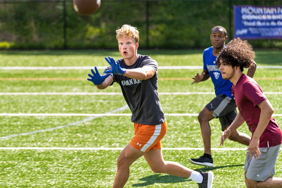 Teens play game of touch football in the park, having fun being active.