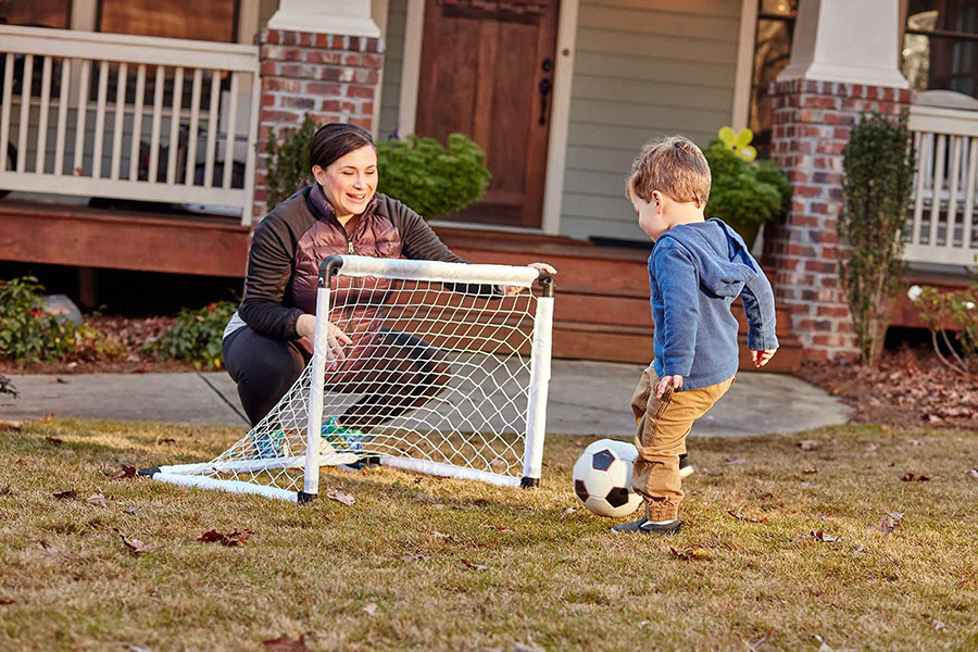 mom and son playing soccer in front yard