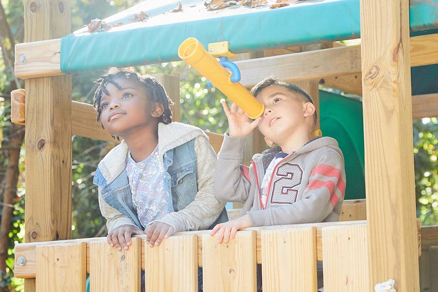 two boys playing on a swingset