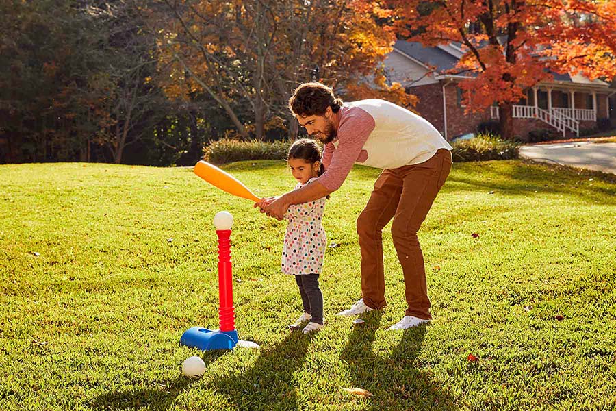 dad and daughter hitting ball off a tee