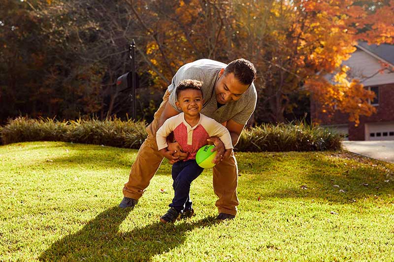dad playing with toddler in backyard