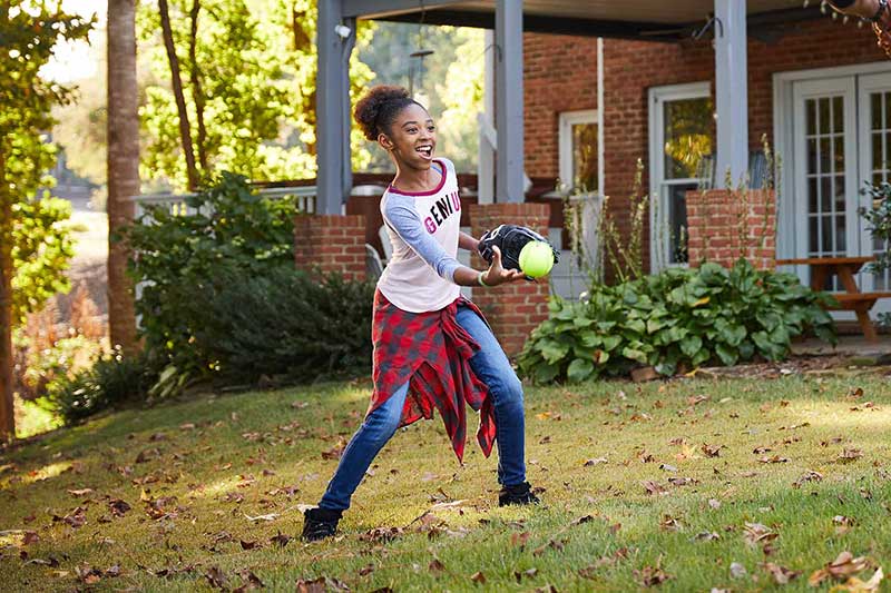 girl playing catch in backyard