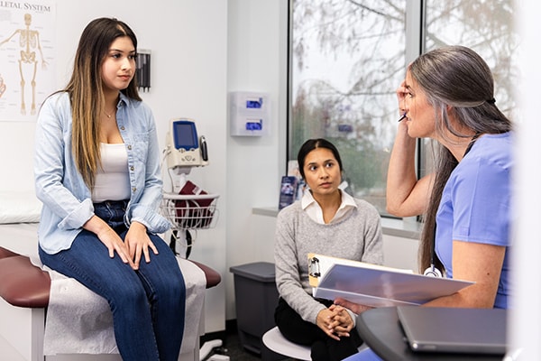 Healthcare provider speaking to teen and parent in exam room