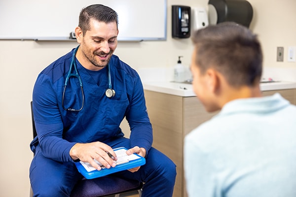 Healthcare provider speaking with teen patient in exam room
