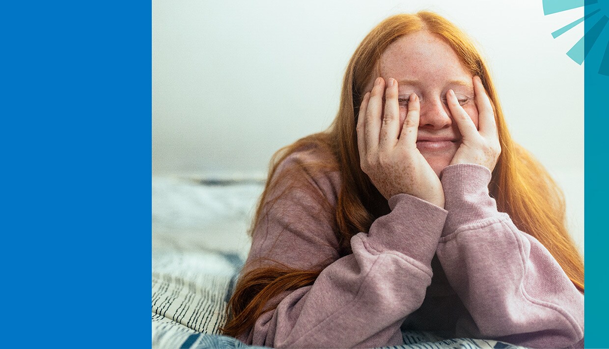 Teen girl holding her head in her hands, smiling