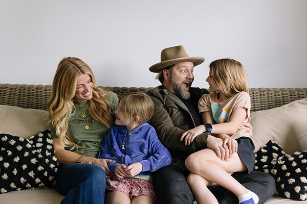 Coy Bowles and his family all looking at one another on the couch in their home