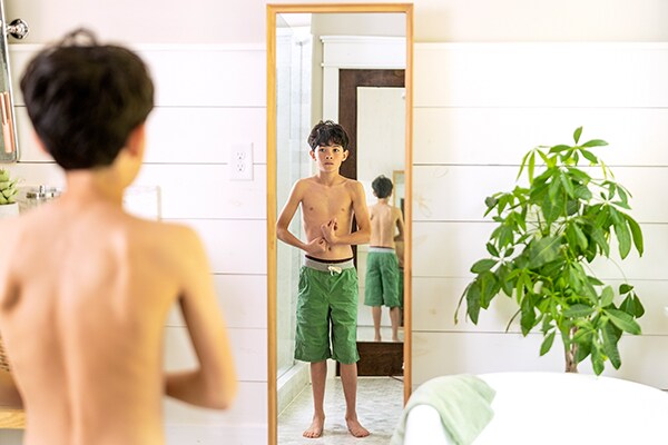 Preteen boy flexing in front of the mirror