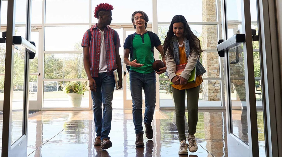 3 teen students walking into middle school
