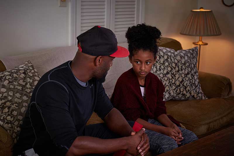 dad talking to daughter on couch