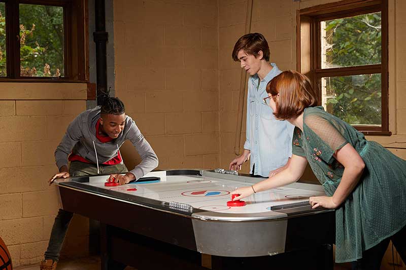 teenagers hanging out and playing air hockey