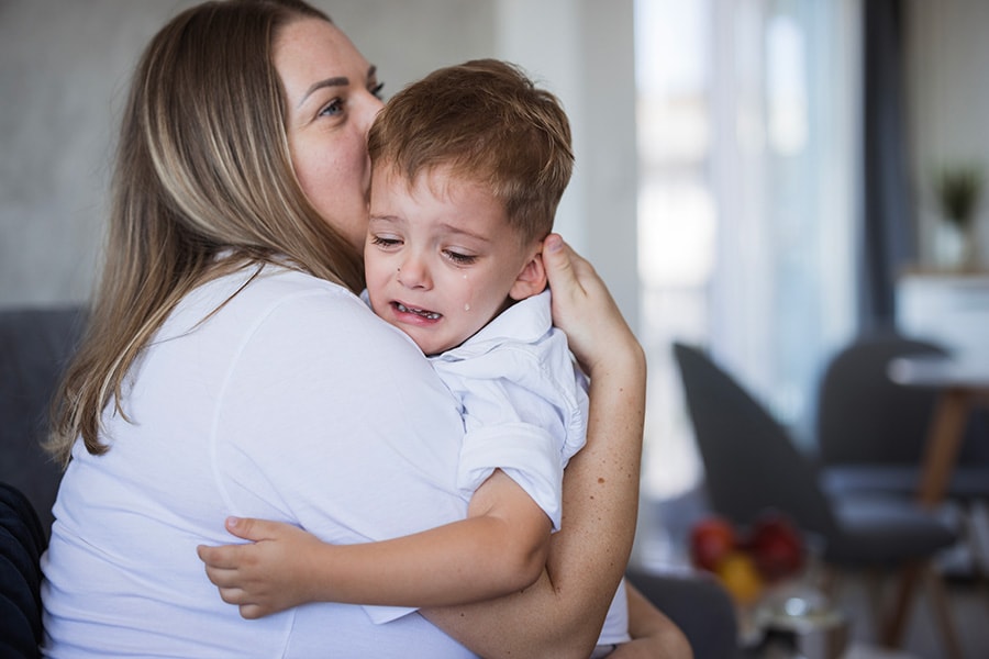 A photo of a mother helping her son with emotional regulation skills by holding him while he cries.