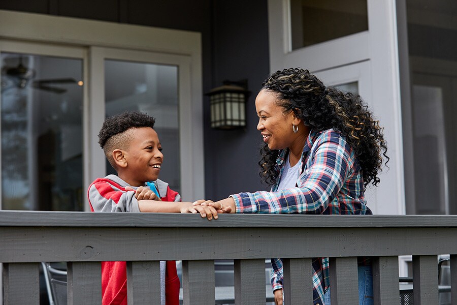 A photo of a mom smiling with her elementary school-aged son outside on the back deck