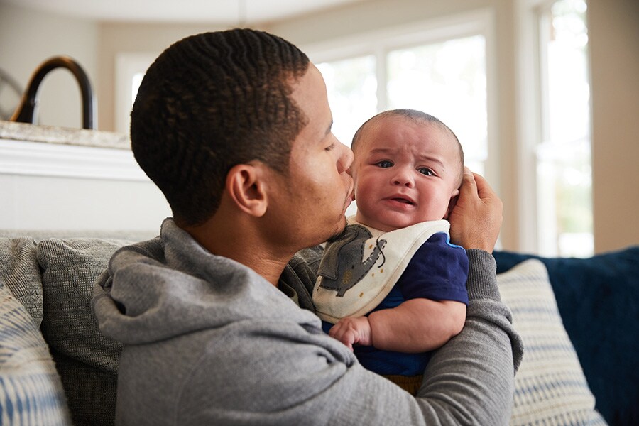A photo of a father calming his infant son by rocking him and using a soothing voice