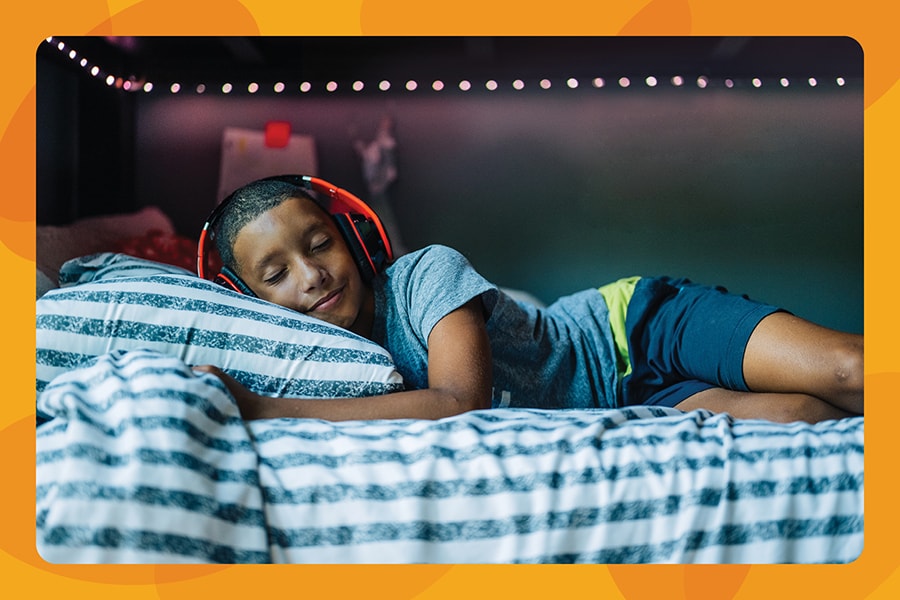 Young boy listens to music while relaxing on his bed