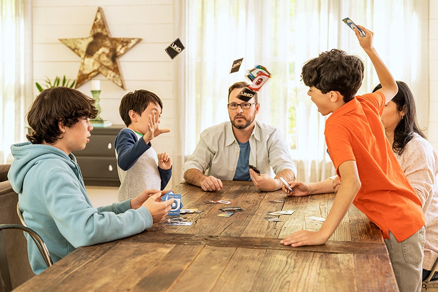 Boy throws cards while playing game with family