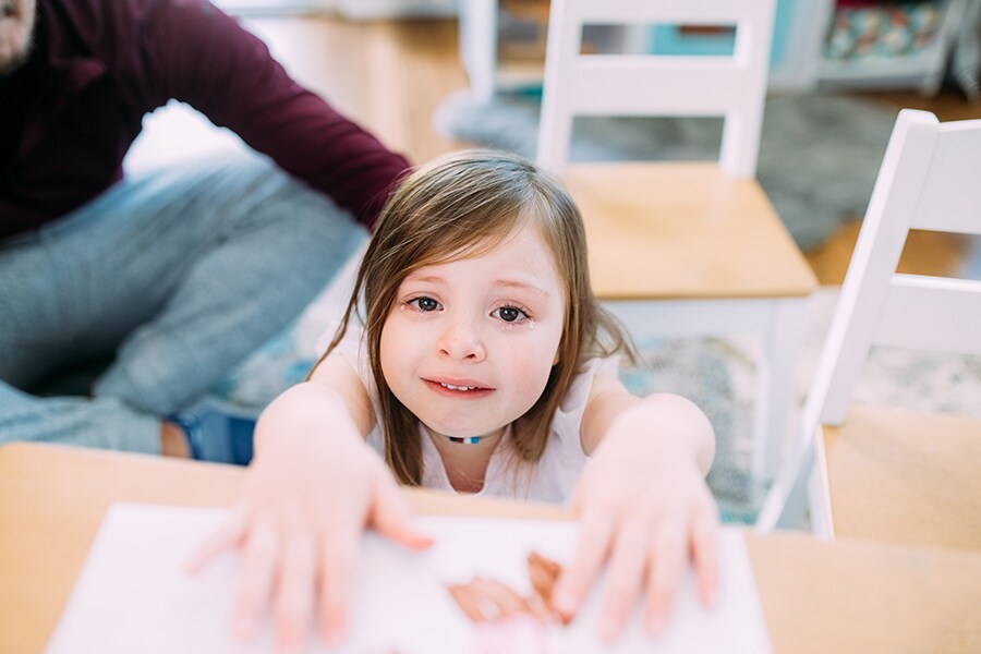 A preschool age girl looks frustrated, sad and disappointed while making a craft