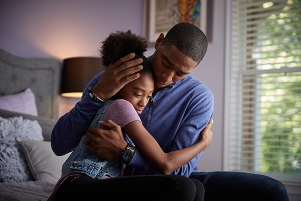 Dad models a nurturing relationship by comforting his daughter to help her emotionally regulate.
