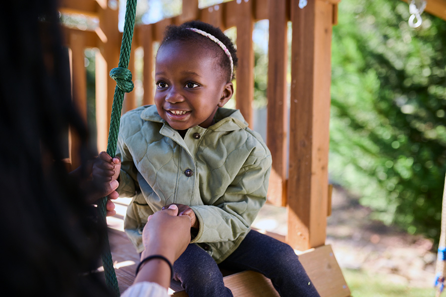 Toddler in winter coat playing outside with parent