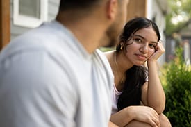 Dad talks with teenage daughter while sitting on front porch.