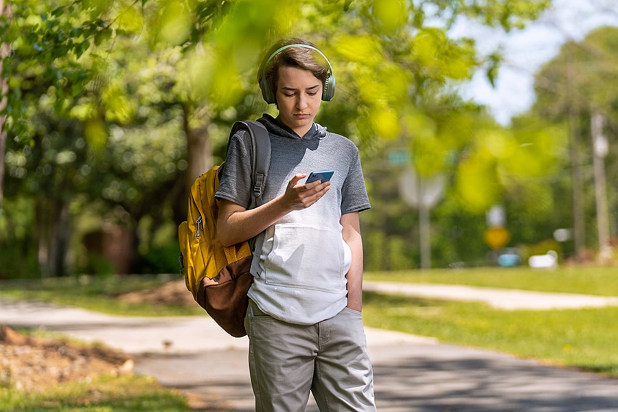 Teenager walking through the park with headphones on