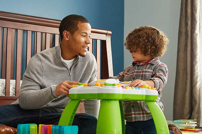 dad playing with toddler son in bedroom