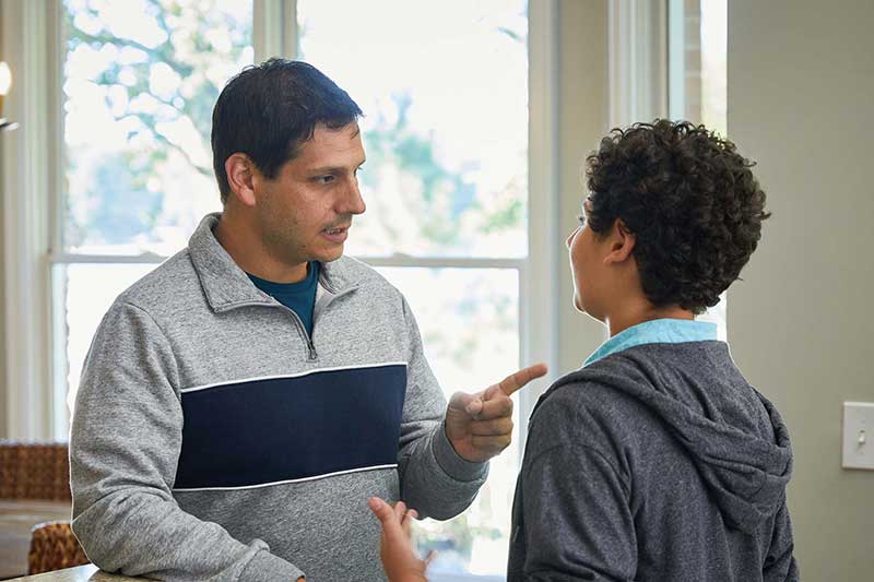 dad reprimanding son in kitchen