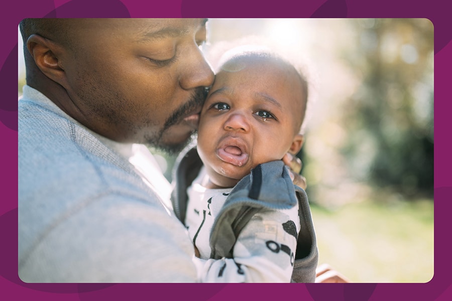 Dad soothing upset infant baby, hugging and kissing him.