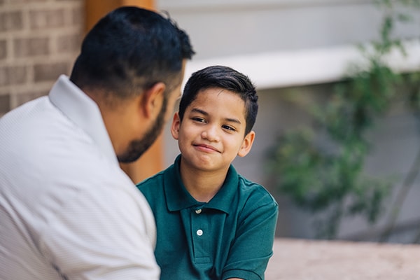 Dad talking to elementary age son on front porch