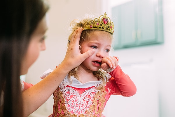 Mom wiping tears off crying little girl's cheek