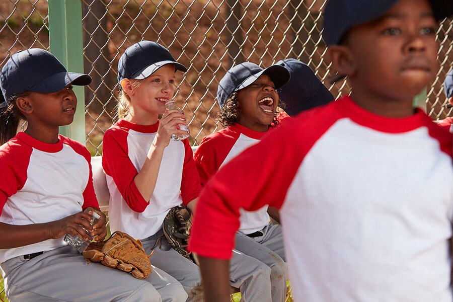 Young kids sitting in the dugout at their baseball game