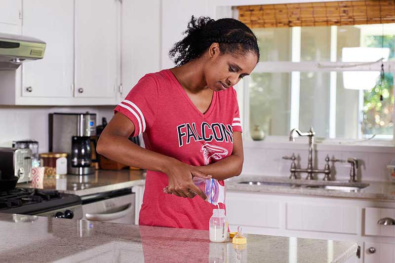 mom pouring breastmilk into bottle