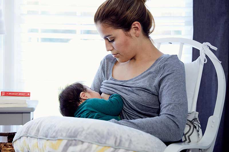 Mom nursing 2-month-old baby in nursery