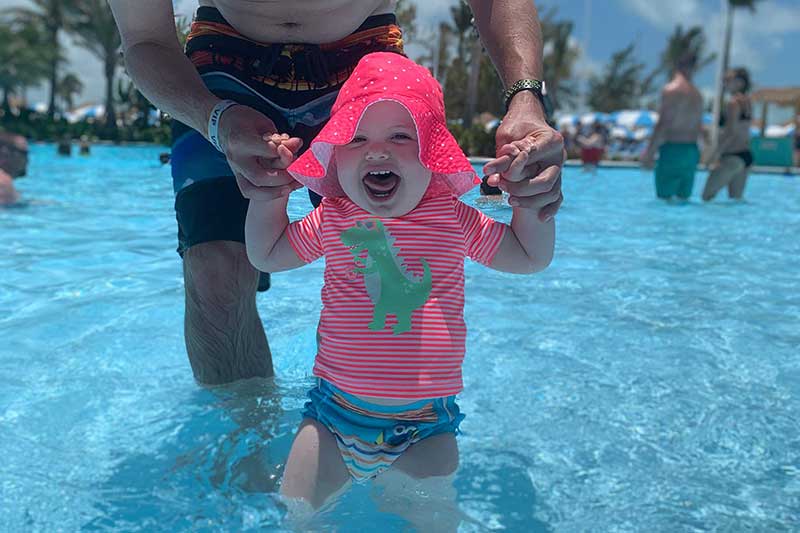 one year old in pool within arm's reach of dad